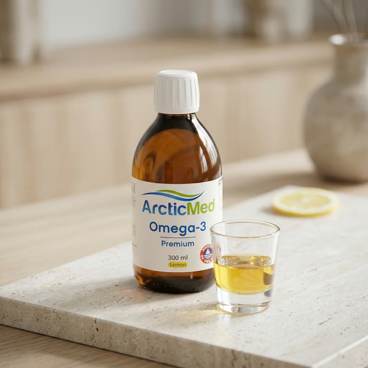 ArcticMed Omega-3 Premium lemon 300 ml bottle next to a glass of oil and a lemon slice on a countertop.